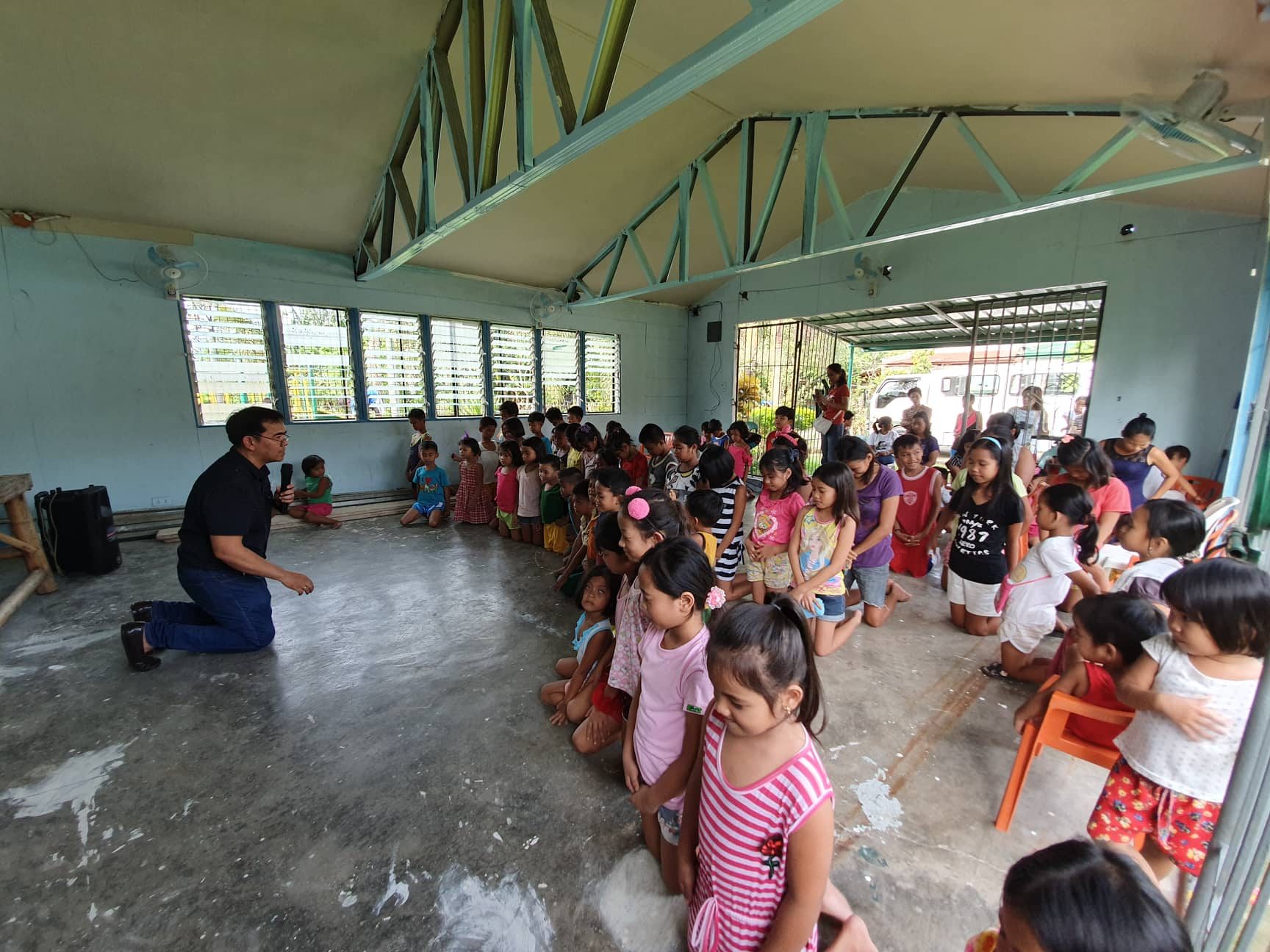Children listening to Bible teaching inside a covered court