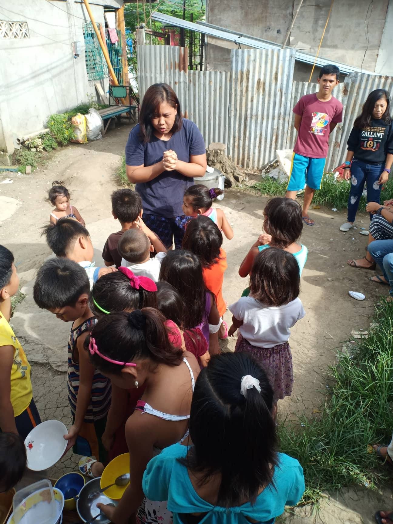 Volunteer praying with children during feeding ministry