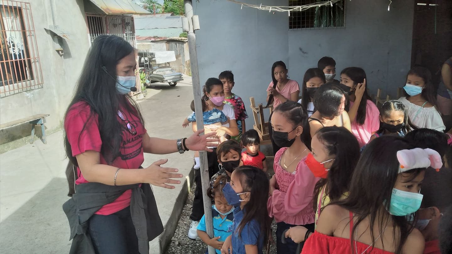Volunteer welcoming children before the feeding program