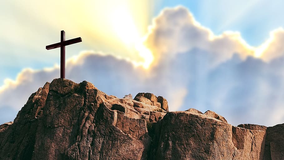 A cross standing on a rock with light breaking through the clouds